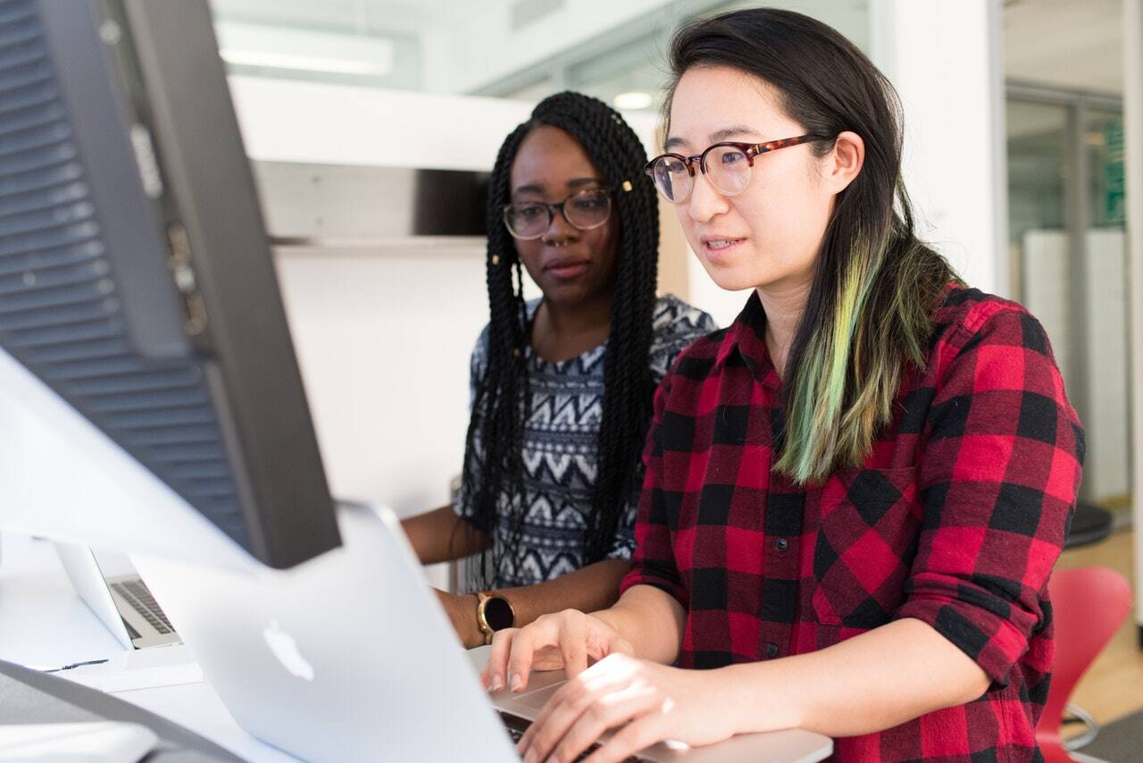 Two women working on a project on a computer Two women working on a project on a computer
